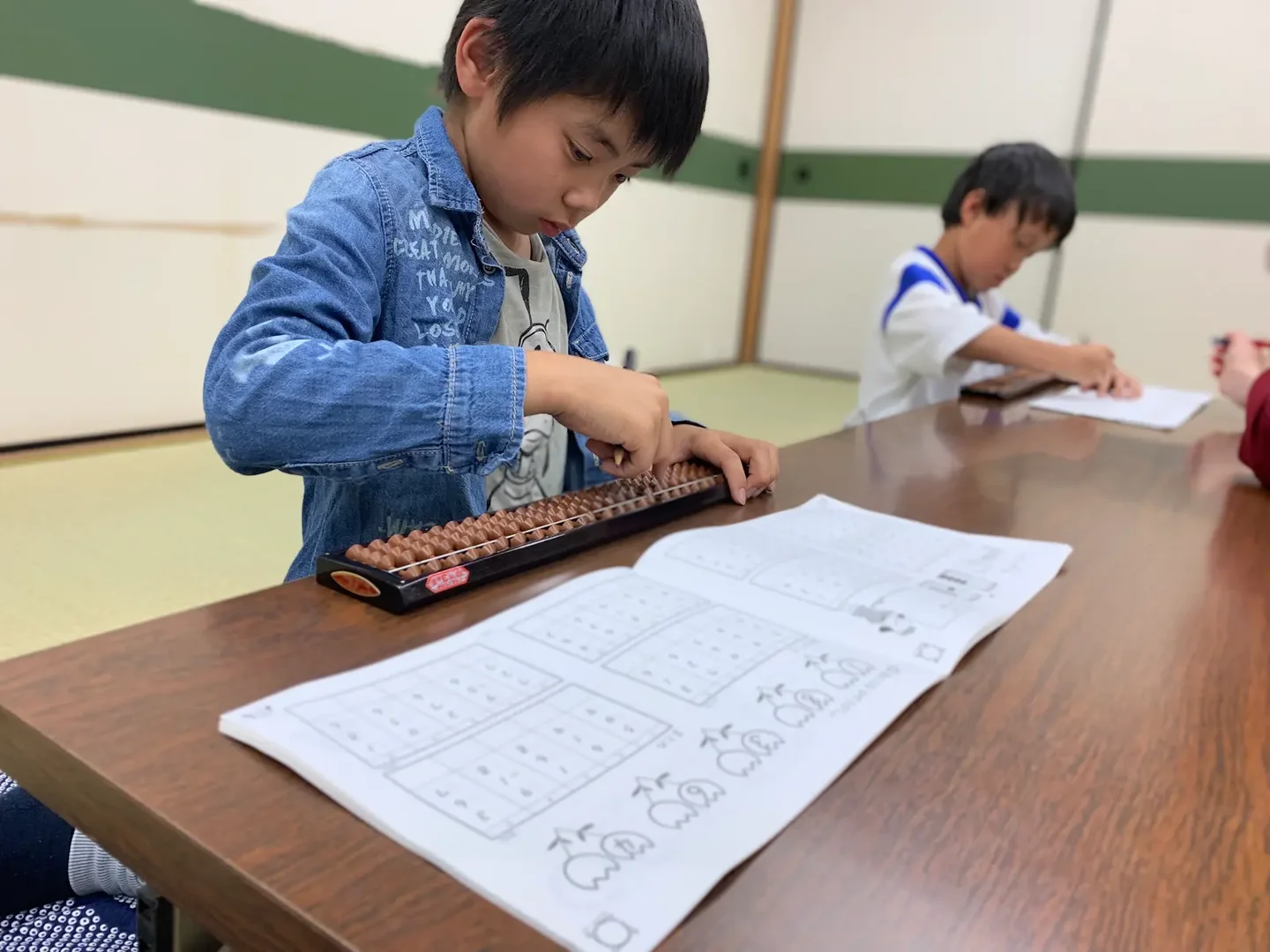 そろばんの珠を動かす、デニムの服の子ども